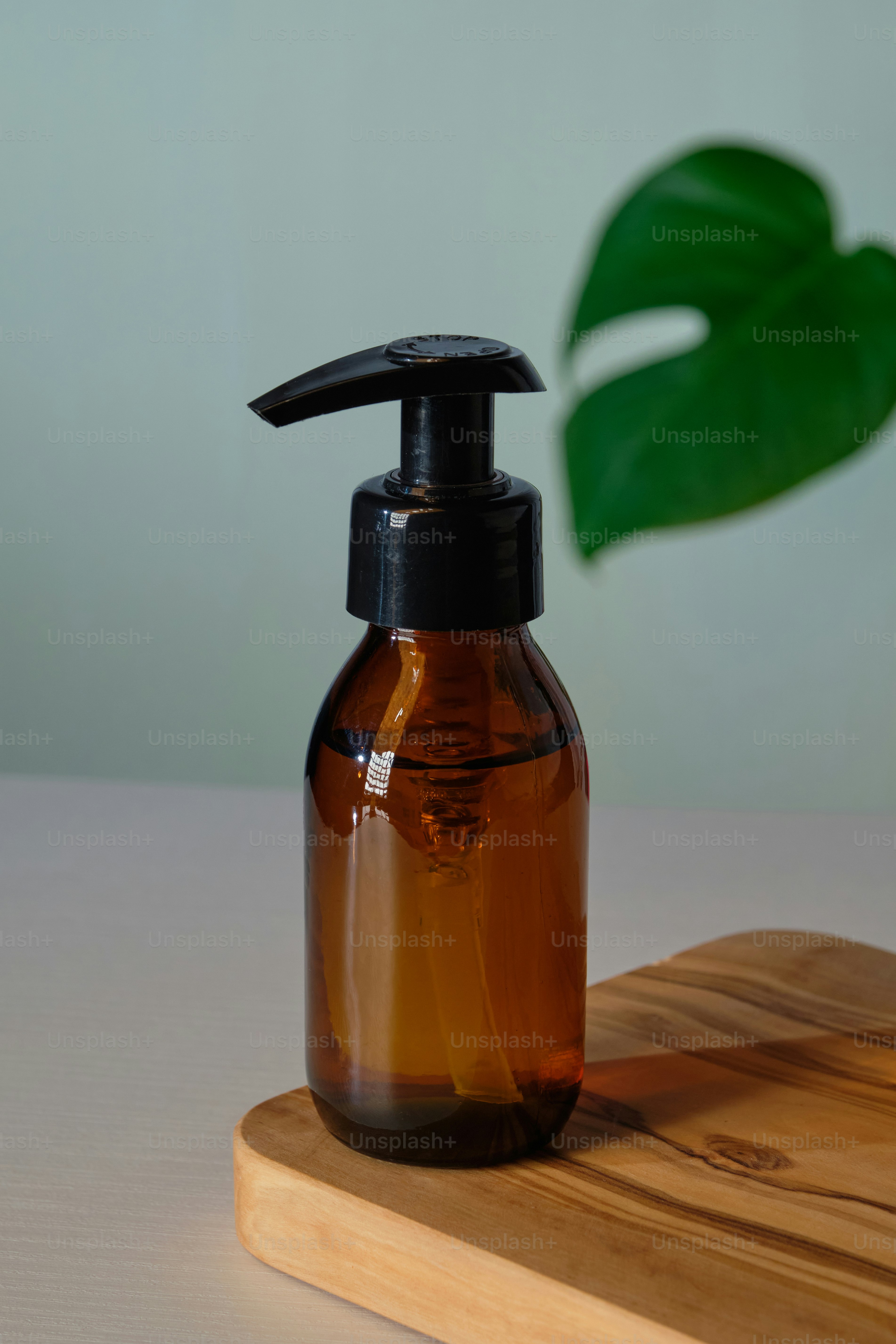 Klares bernsteinfarbenes Glaspumpenflaschenmodell mit tropischem grünem Blatt. Spenderverpackungsdesign für natürliche Biokosmetik.