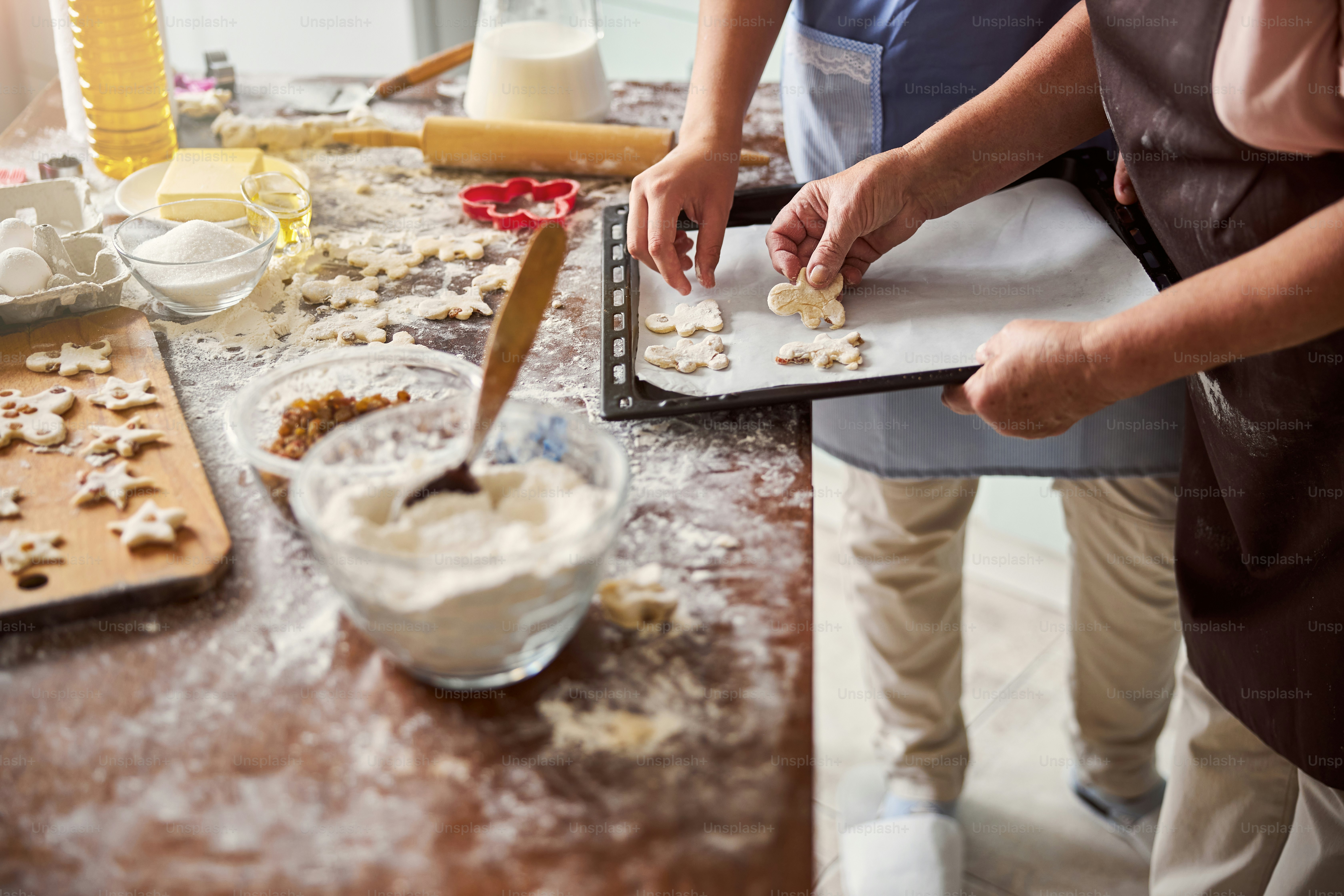 Cropped photo of two people involved into cookie baking process in cozy