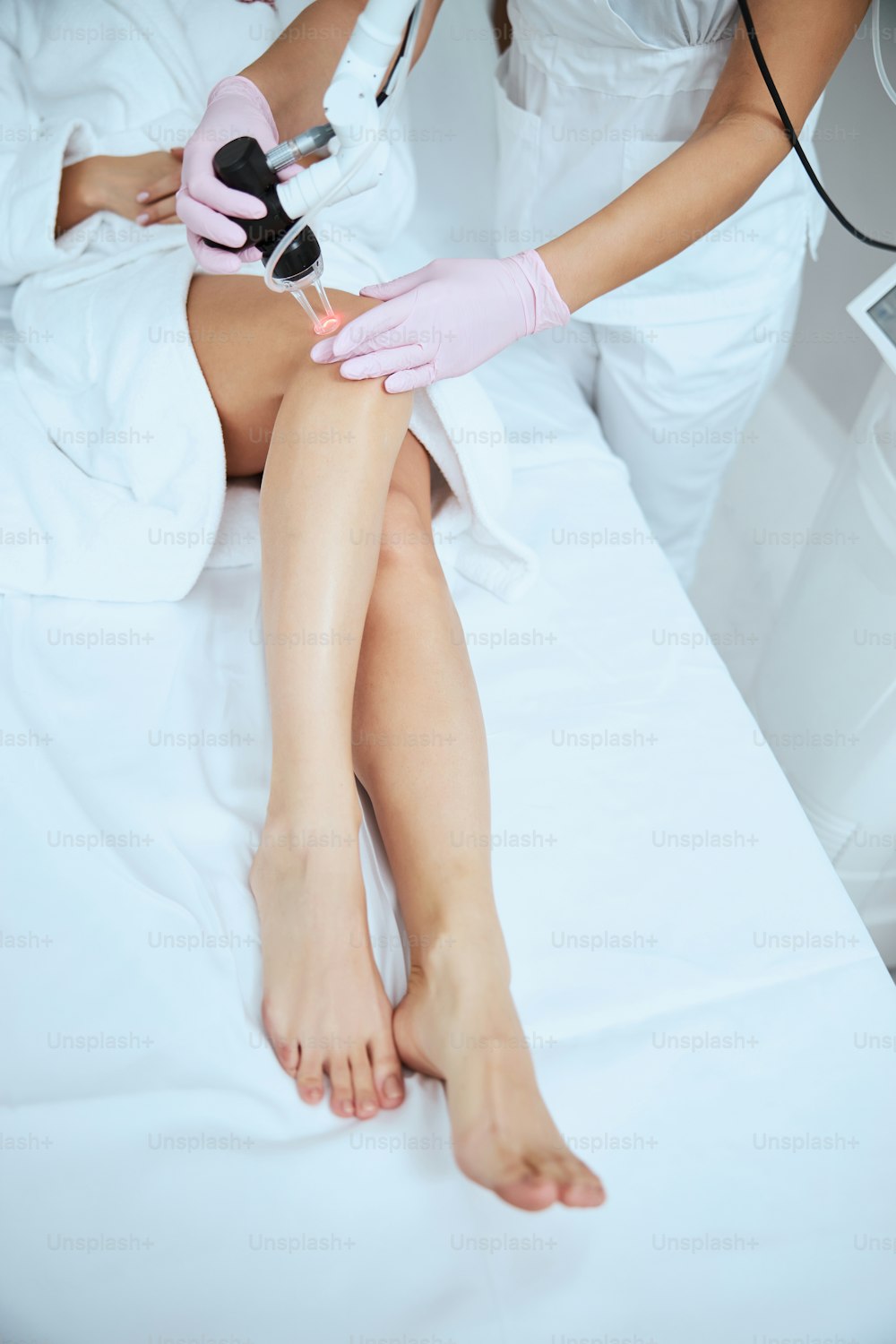 美容クリニックで若い女性患者に非侵襲的な処置を行う医師のトリミングされた写真