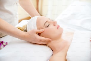 Caucasian woman resting on massage bed and get facial spa  treatment with essential oil from professional therapist at beauty salon