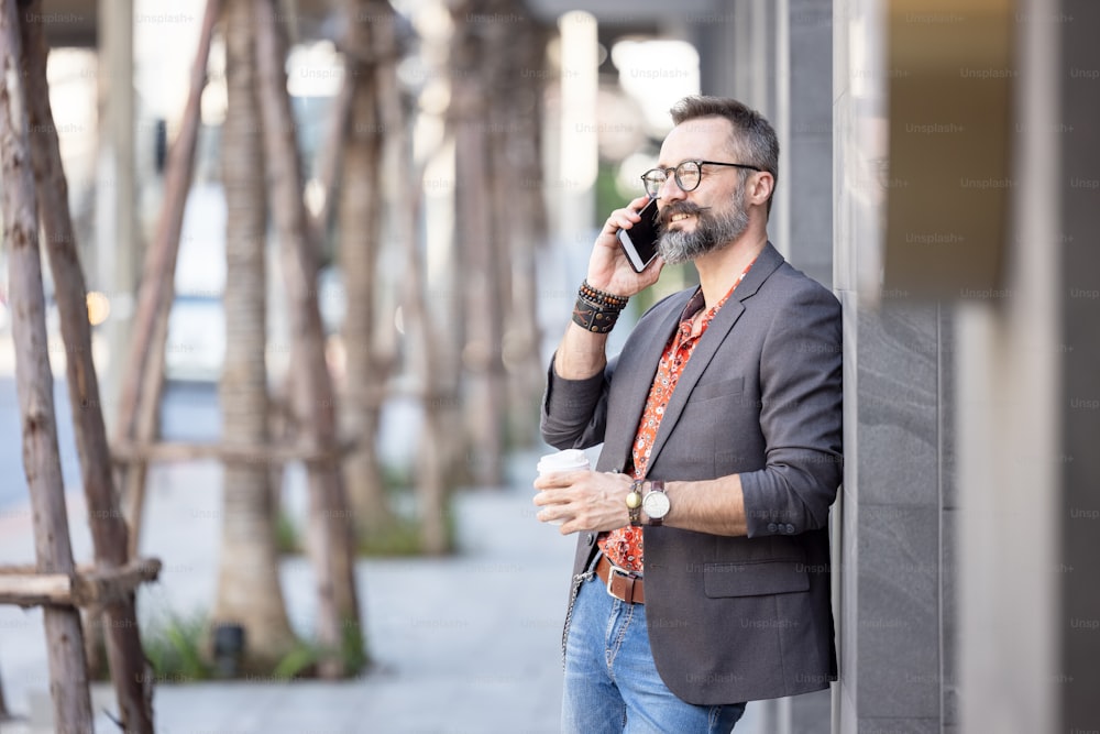 Uomo d'affari con caffè usando il telefono cellulare.