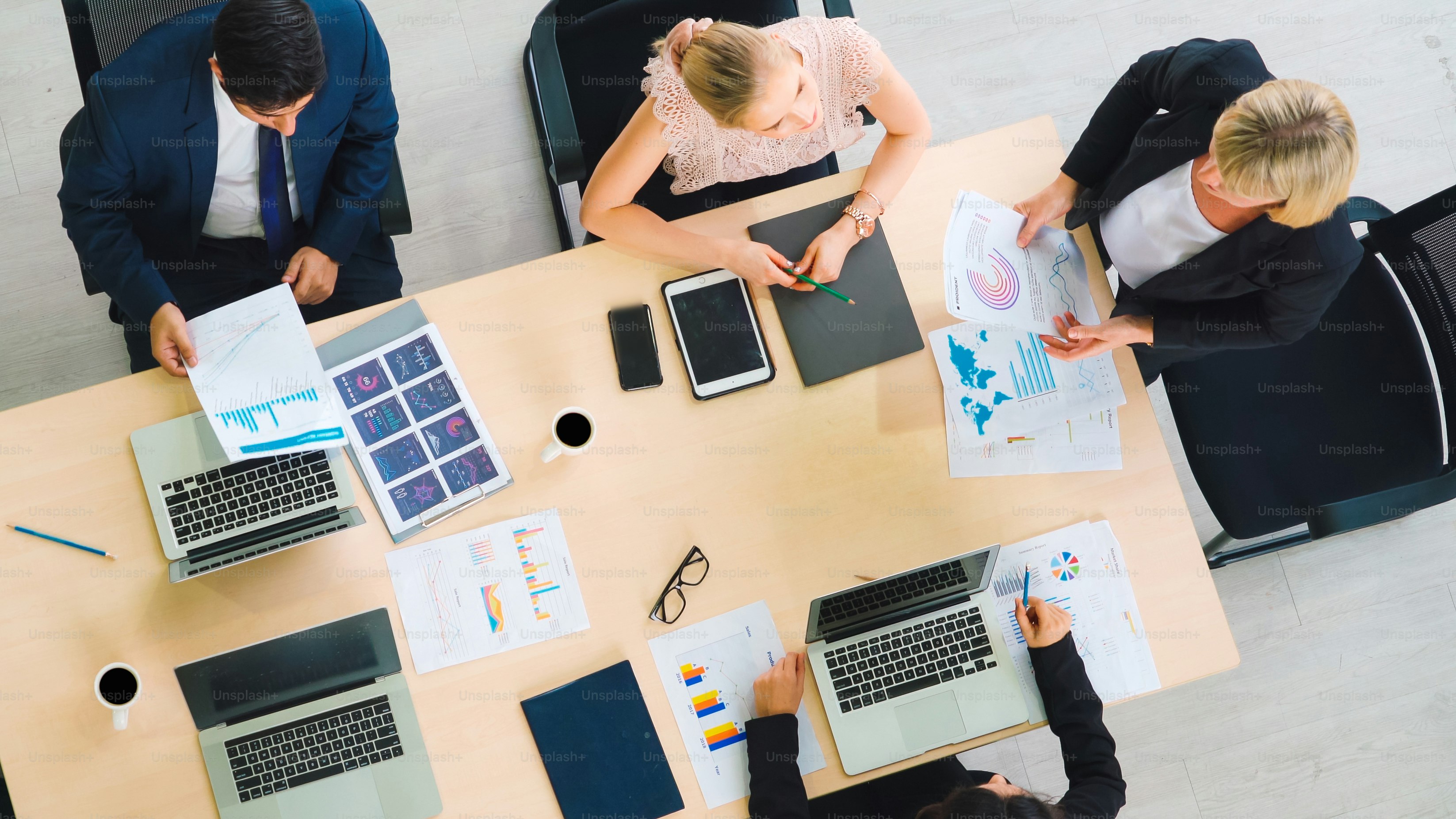 Geschäftsleute-Gruppentreffen aus der Draufsicht im Büro aufgenommen. Beruf Geschäftsfrauen, Geschäftsleute und Büroangestellte, die in einer Teamkonferenz mit Projektplanungsdokument auf dem Besprechungstisch arbeiten.