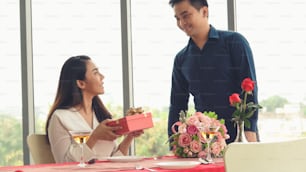 Romantic couple giving gift to lover at restaurant . Happy couple lifestyle .
