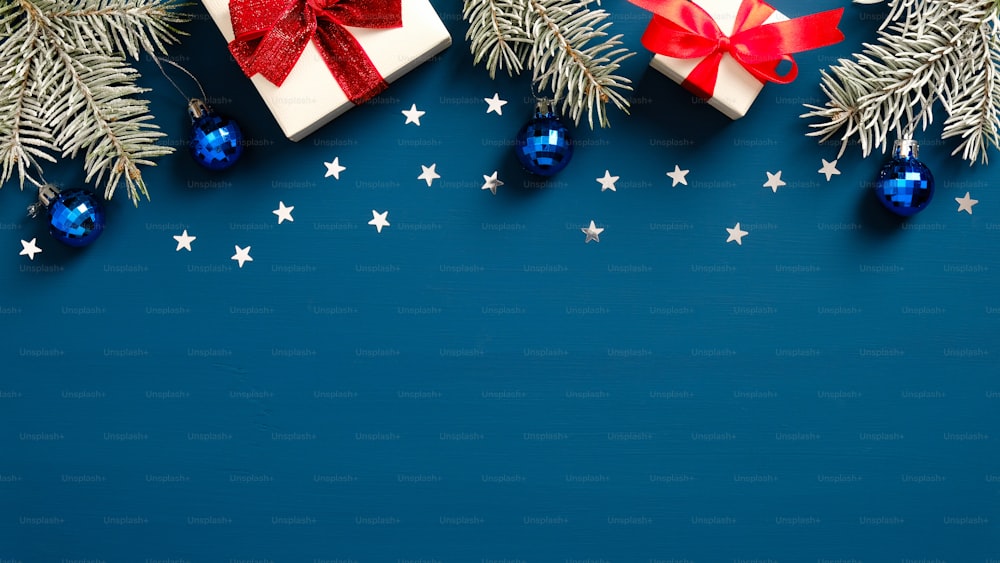 Christmas and New Year banner with fir branches, white gift boxes with red ribbon bows and Christmas balls on dark blue background. Flat lay, top view.