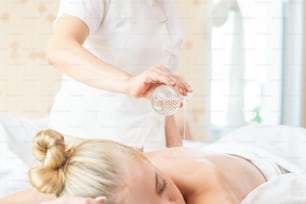 Caucasian woman resting on massage bed and get back spa treatment with essential oil from professional therapist at beauty salon
