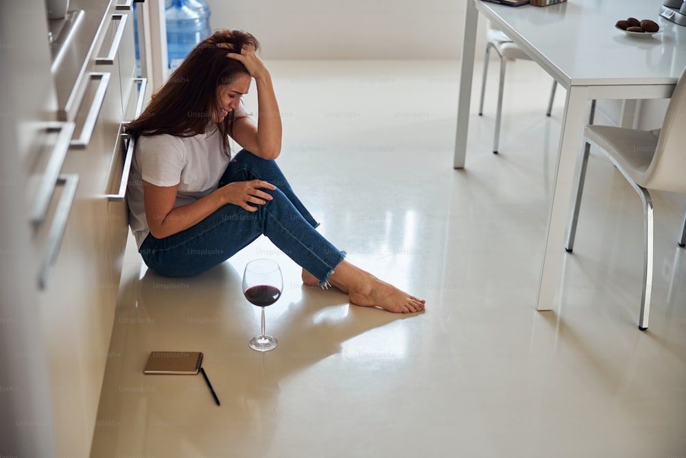 Young depressed woman sitting on the floor and touching her hair while crying