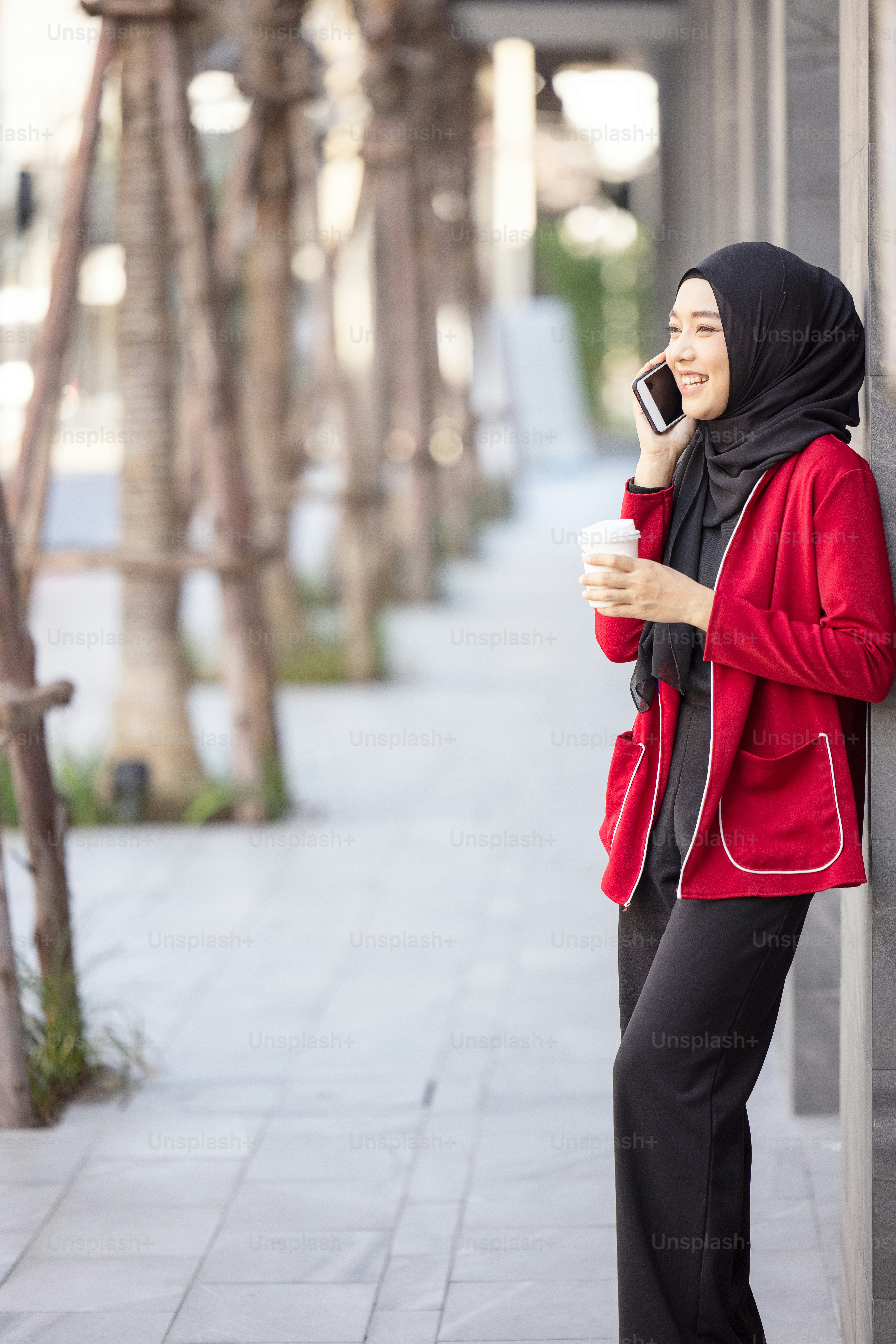 Successful operation. Arab businesswomen in hijab holding a coffee in the street and holding a cell phone