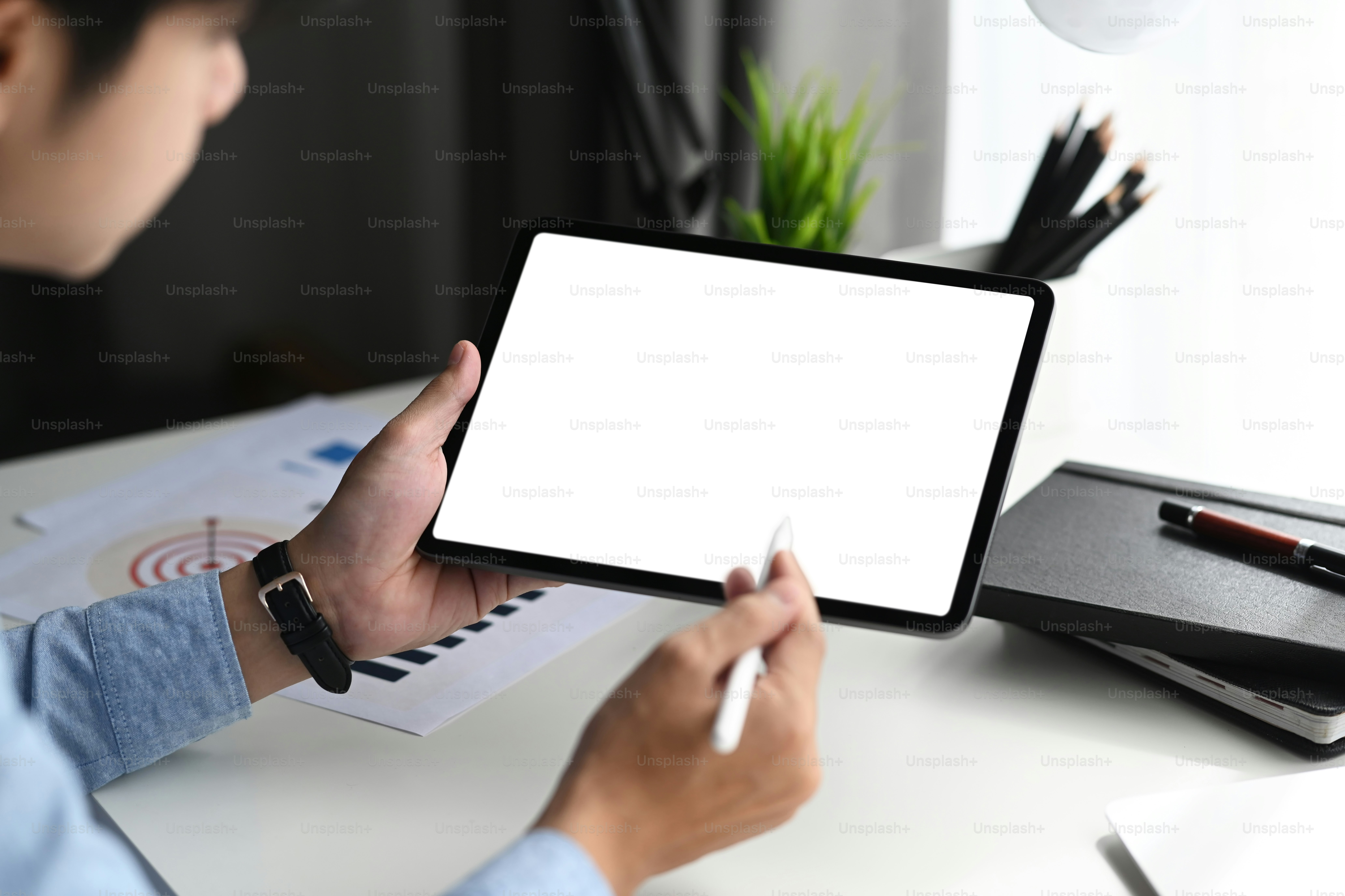 Young graphic designer with stylus pen pointing on graphic tablet with blank screen.
