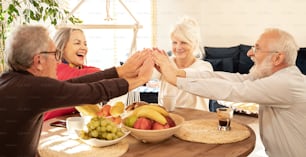 Grupo de personas mayores celebrando el éxito juntos en casa. Concepto de jubilación feliz.