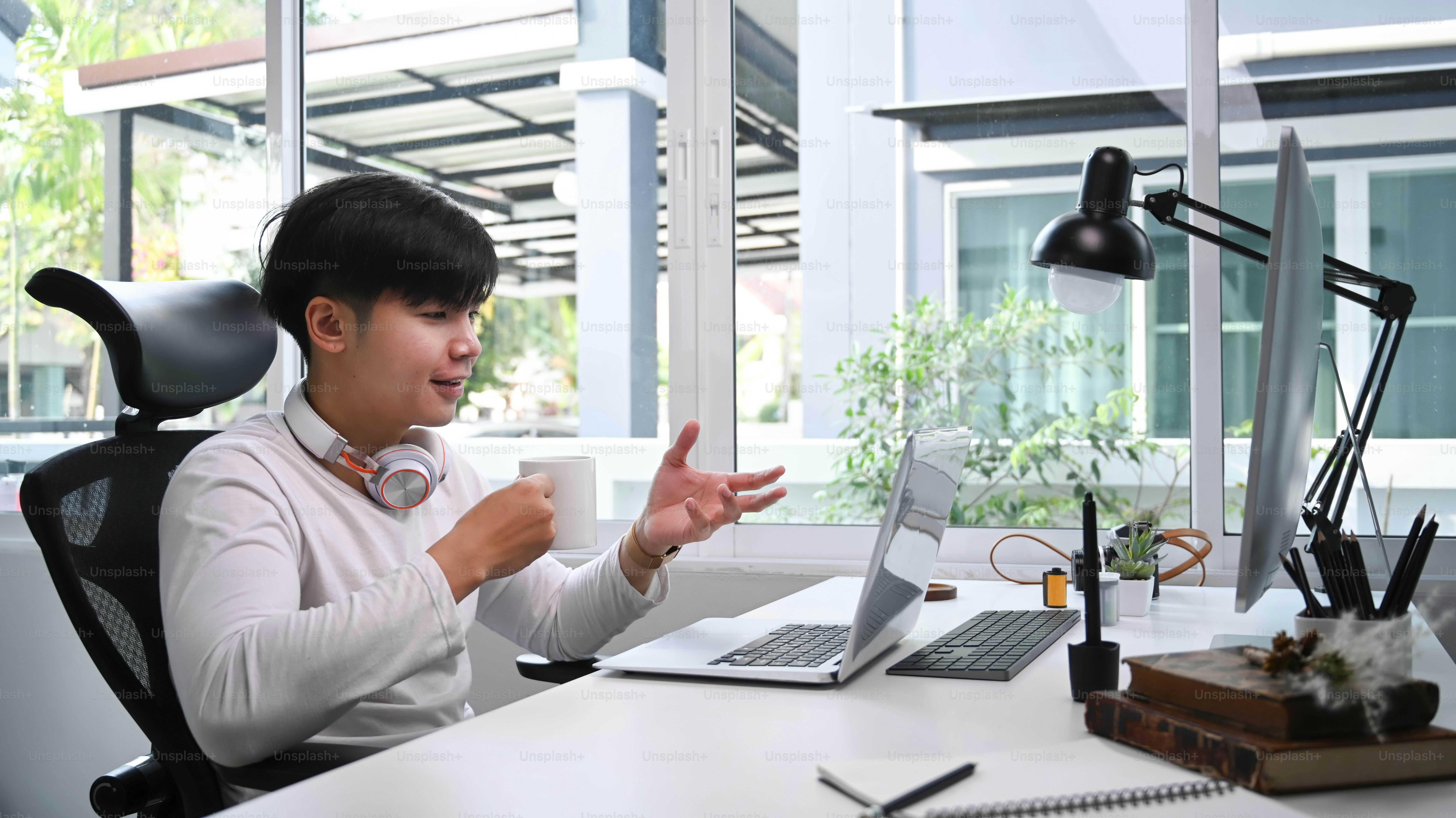 A cheerful man with headphone having video conference meeting with computer at home.