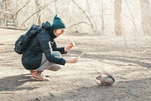 Kaukasische Frau fotografiert Eichhörnchen im Park. Touristenreisendes Mädchen macht Smartphone-Fotos von wilden Tieren im Wald. Lustige Outdoor-Aktivitäten und Bloggen Vlogging online.