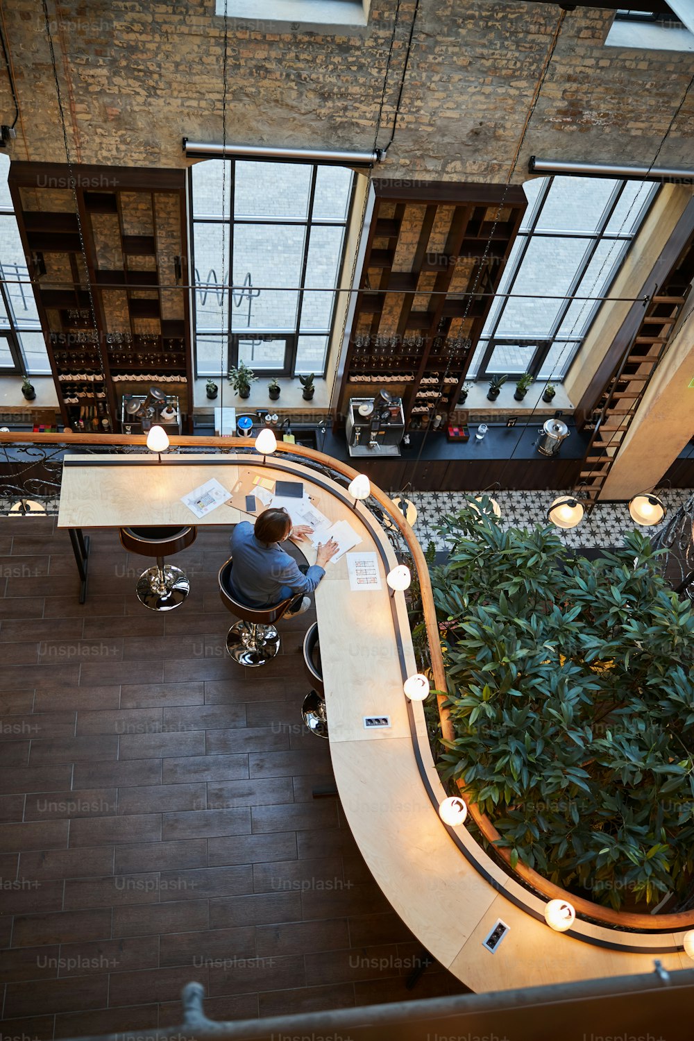 Foto vista dall'alto di un uomo concentrato che lavora sodo mentre è seduto al tavolo nella lounge dell'hotel