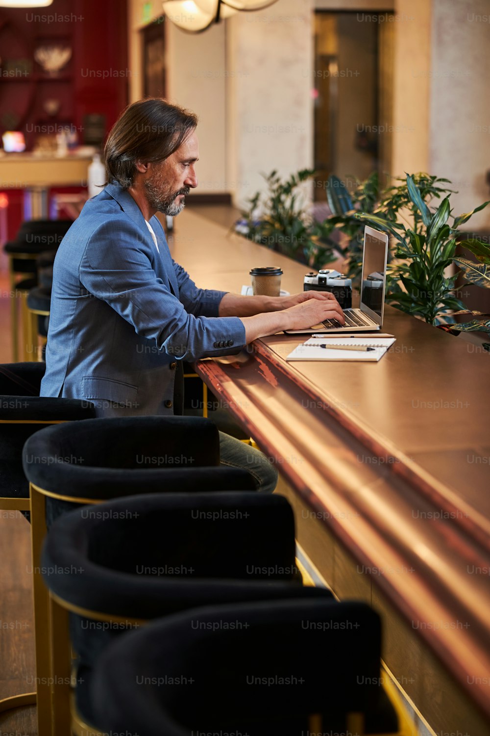 Empresário trabalhador digitando em seu laptop enquanto trabalha remotamente a partir de um lounge de hotel