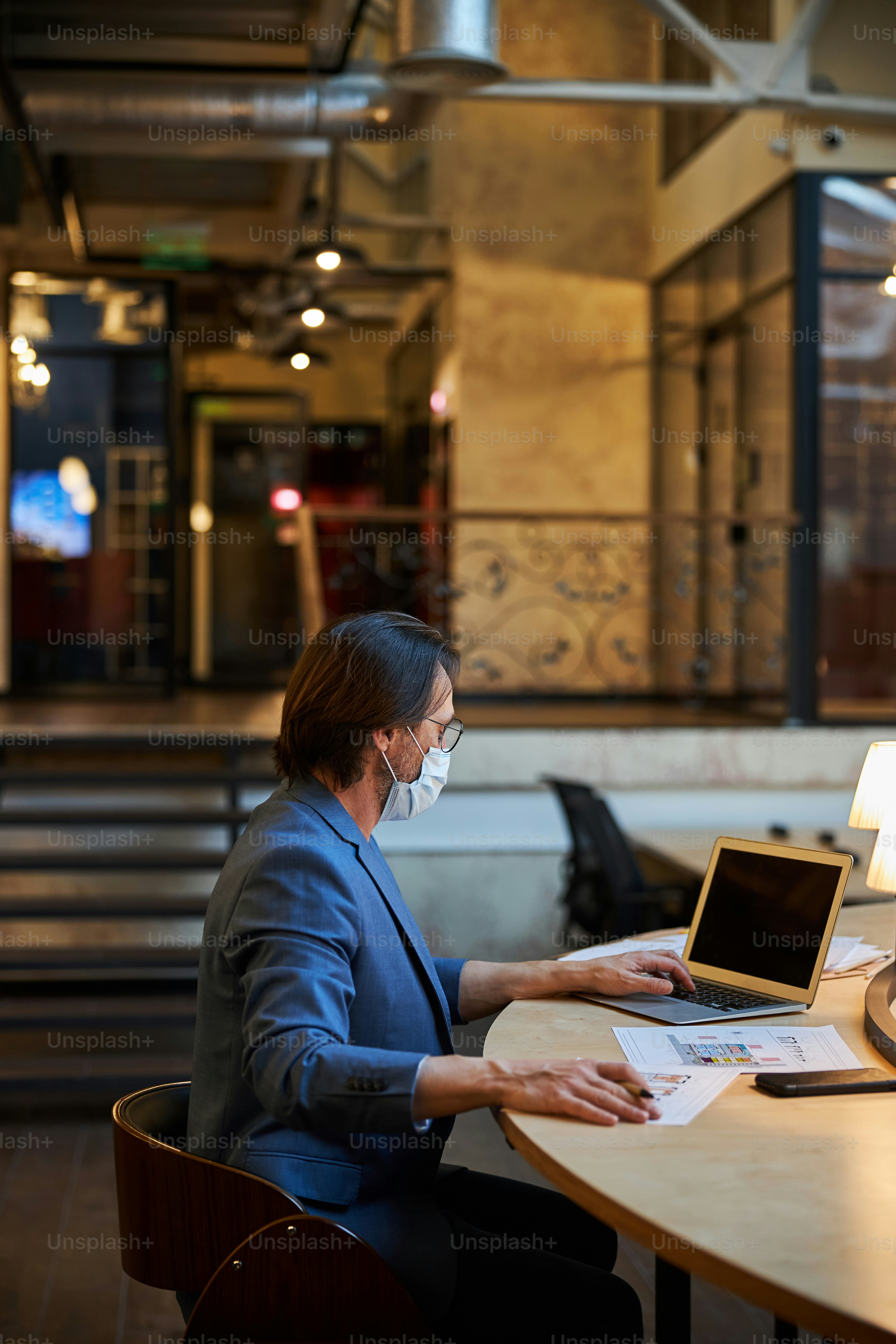 Verantwortungsbewusster Bürger mit Schutzmaske, der die öffentliche Lounge zum Arbeiten aus der Ferne nutzt