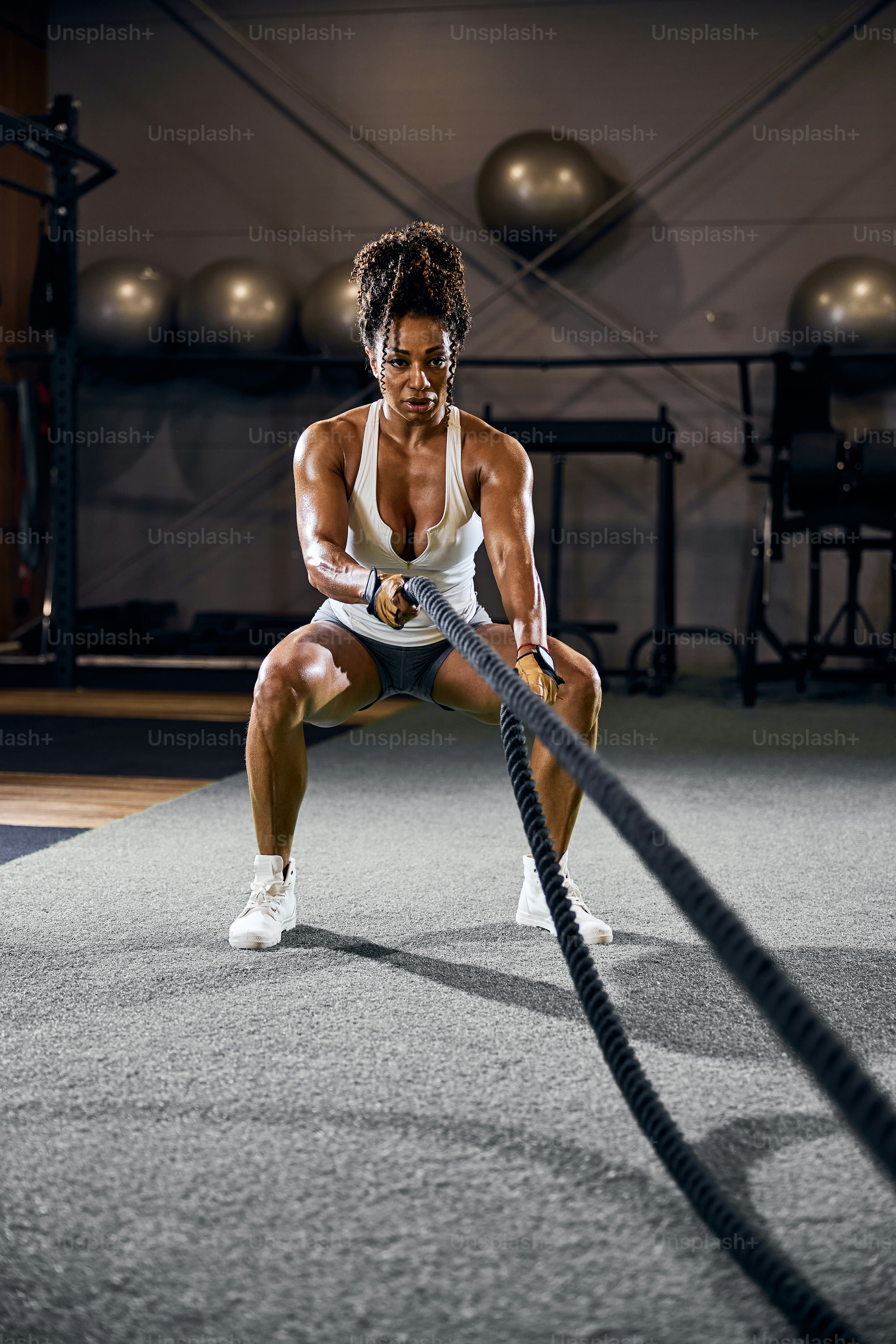 Black woman using battle ropes at the gym