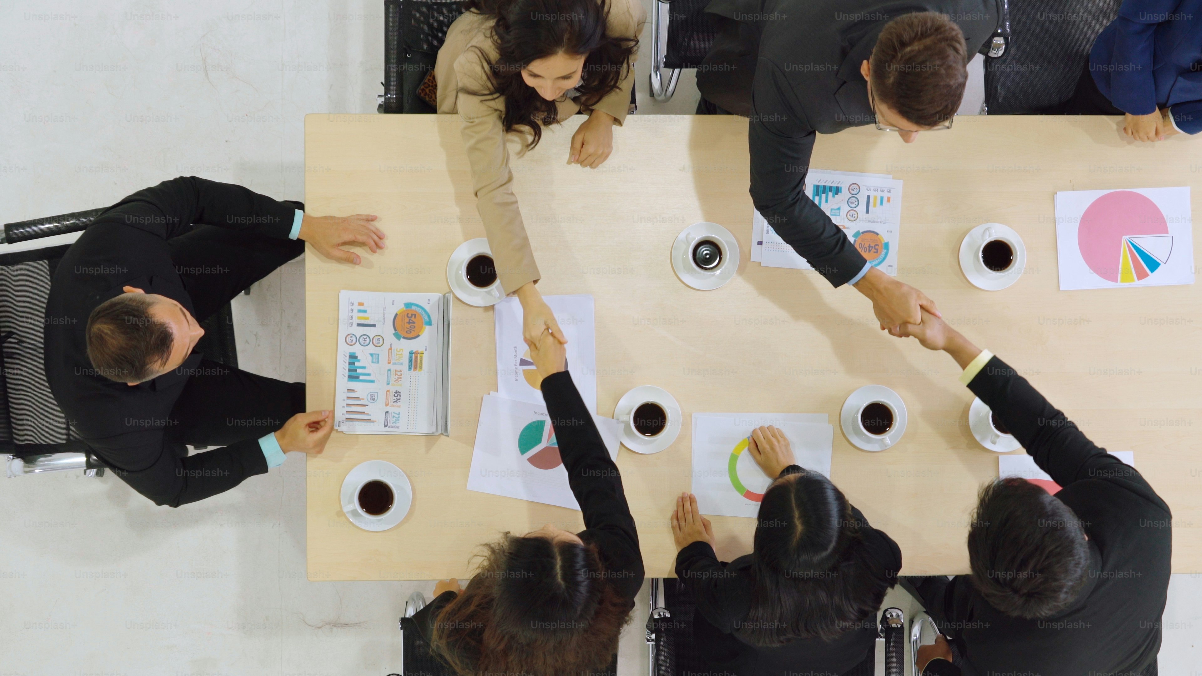 Group business people handshake at meeting table in office together with confident shot from top view . Young businessman and businesswoman workers express agreement of investment deal.
