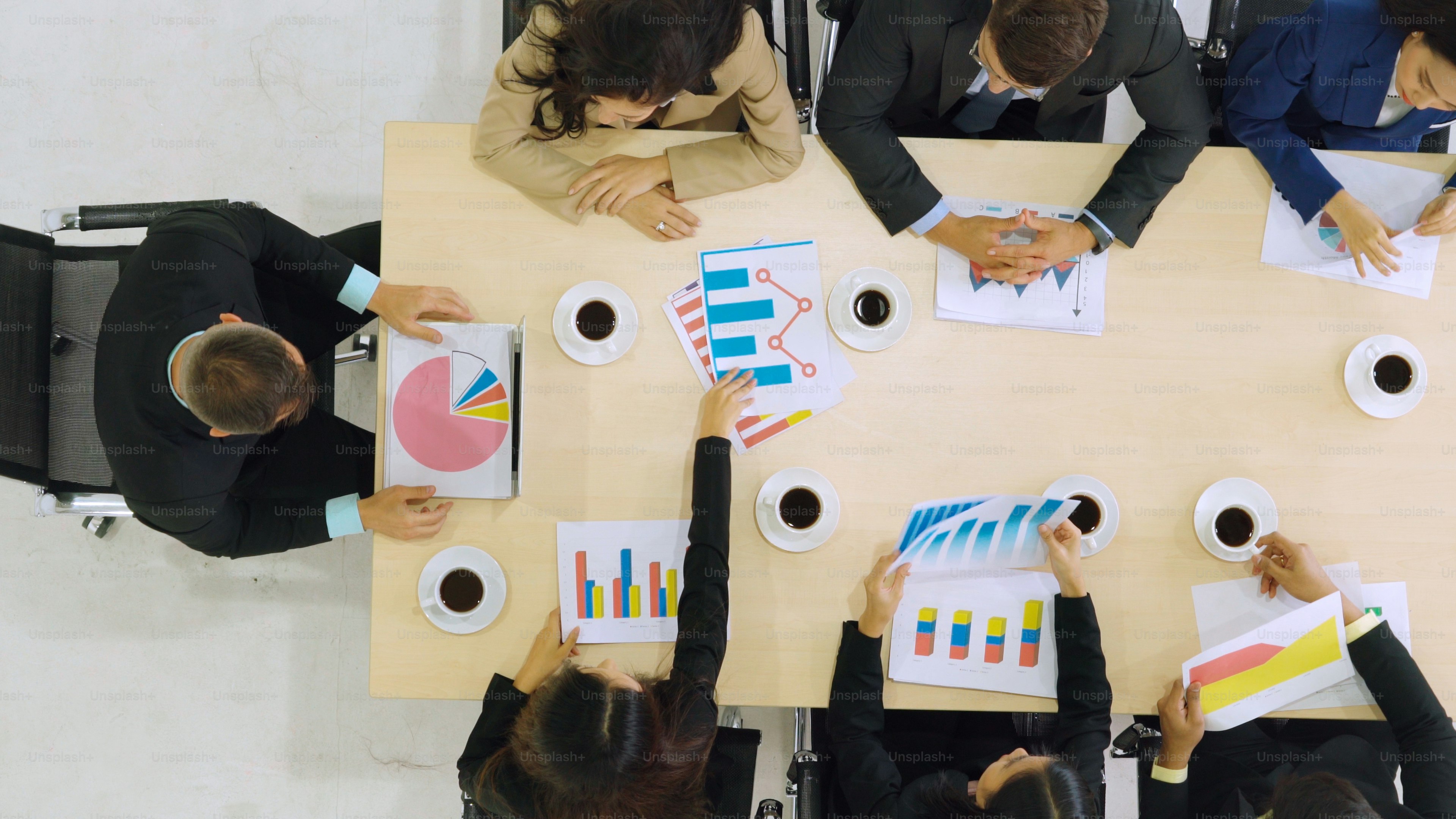 Geschäftsleute-Gruppentreffen aus der Draufsicht im Büro aufgenommen. Beruf Geschäftsfrauen, Geschäftsleute und Büroangestellte, die in einer Teamkonferenz mit Projektplanungsdokument auf dem Besprechungstisch arbeiten.