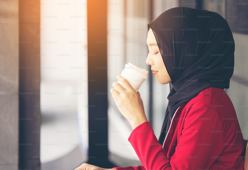 Modern Muslim Woman walking across the street with a take-away coffee