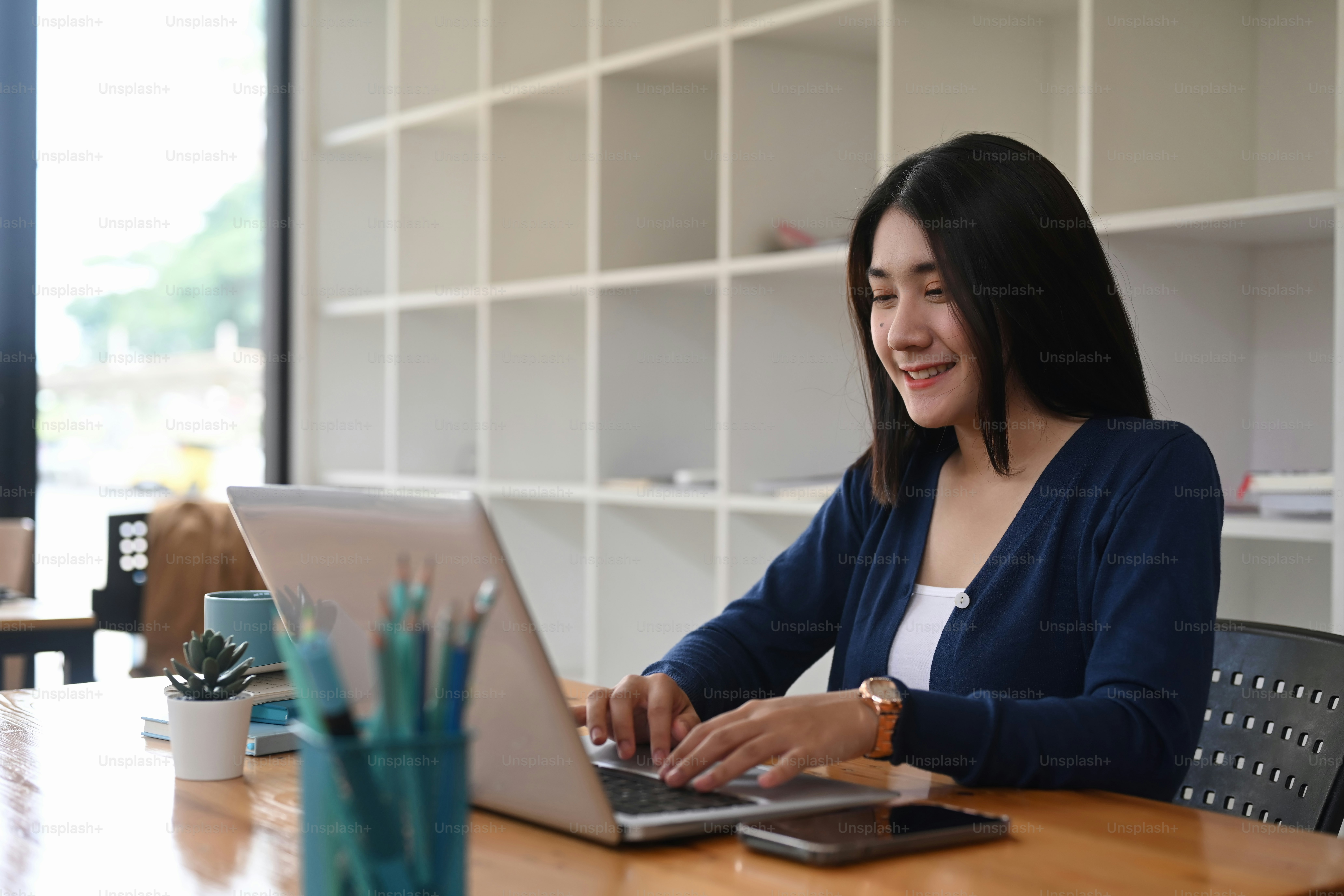 Une jeune designer travaillant en freelance parcourt les informations du projet sur un ordinateur portable au poste de travail créatif.