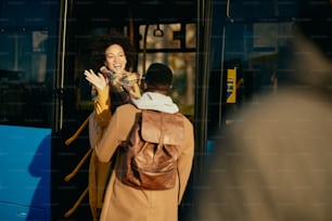 Mulher afro-americana feliz entrando em um ônibus e acenando para seu namorado na estação.