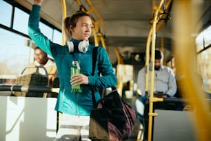 Atleta feminina pensativa viajando de transporte público e olhando para o lado.