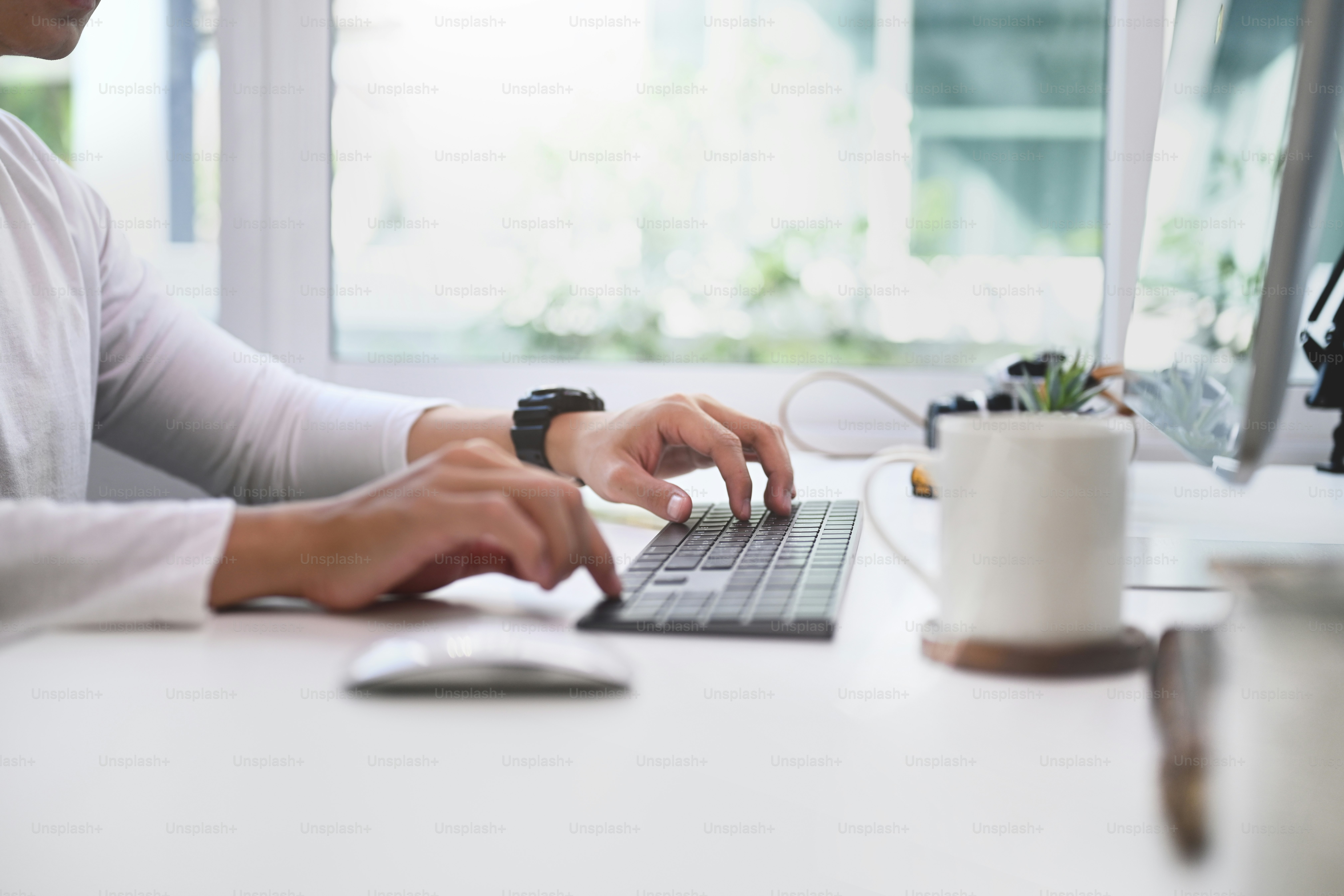 Close up view of young man hands typing on a keyboard of computer.