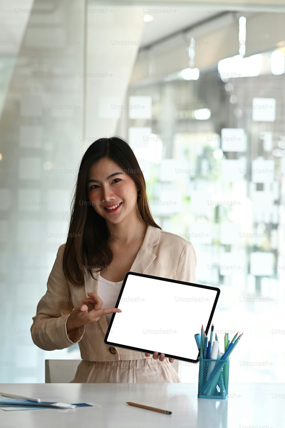 Portrait of young beautiful businesswoman showing tablet. Blank screen for graphics display montage.