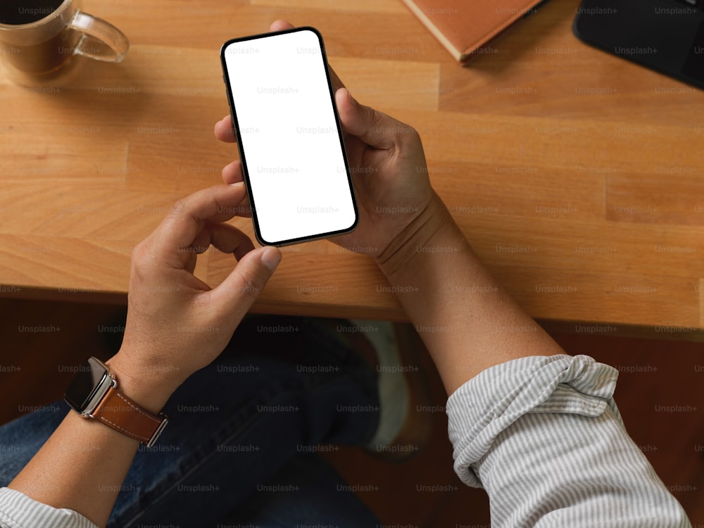 Draufsicht der Geschäftsmannshände mit Smartphone auf Holztisch, einschließlich Clipping-Pfad