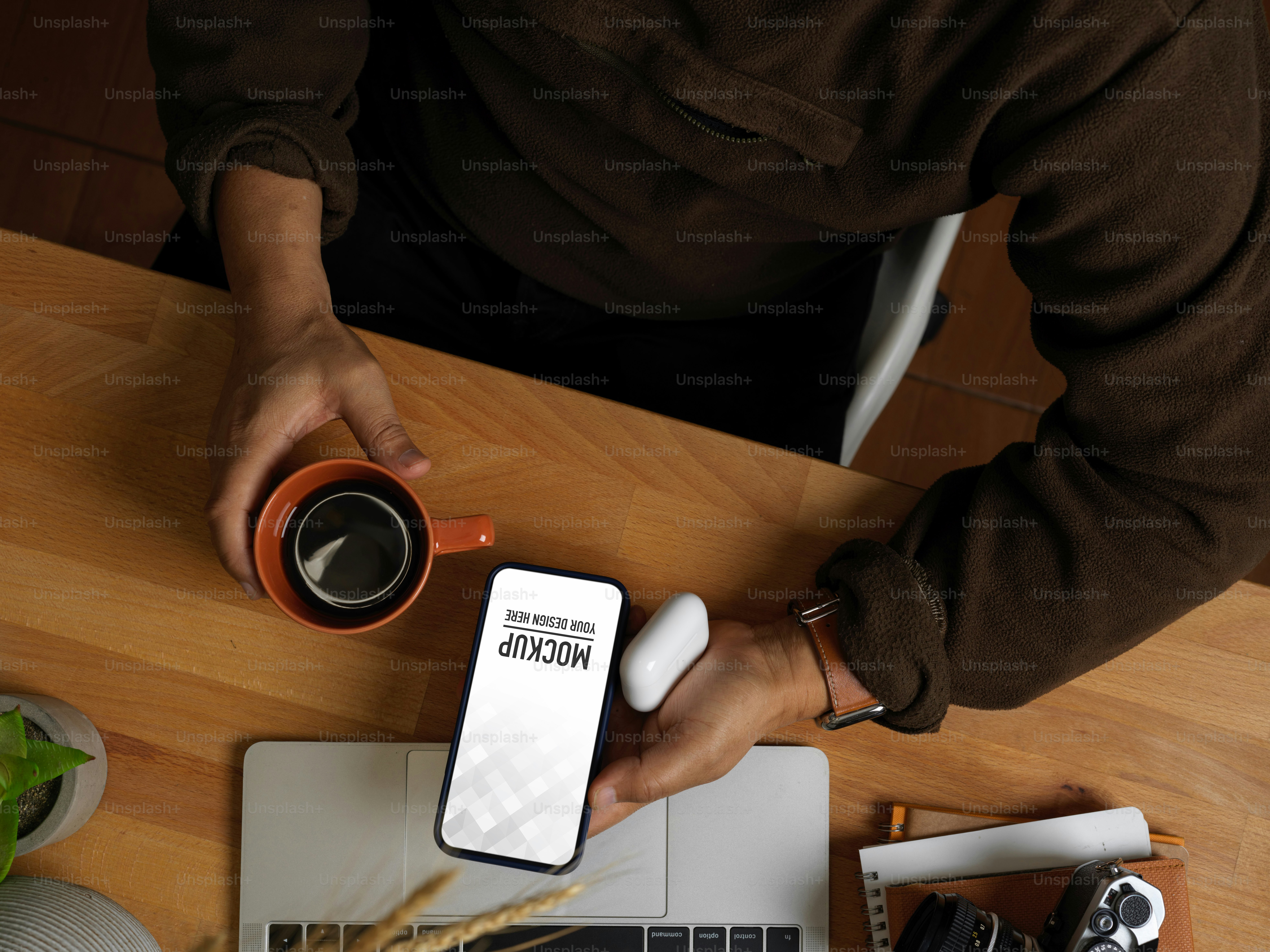 Vista dall'alto della mano maschile che utilizza lo smartphone e tiene la tazza di caffè sul tavolo da lavoro, percorso di ritaglio