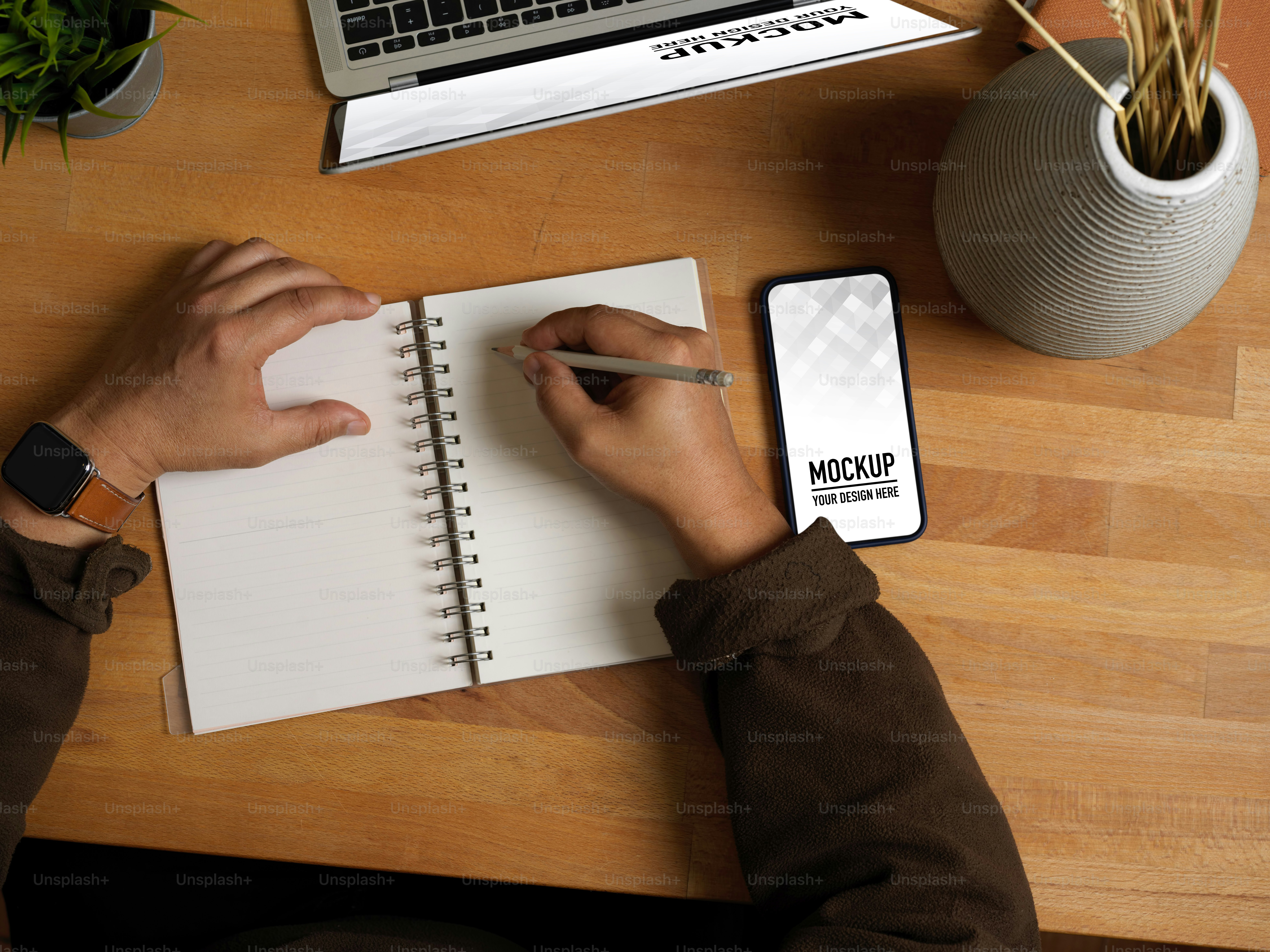 Vista superior da escrita da mão masculina no caderno em branco na mesa de trabalho de madeira com decoração