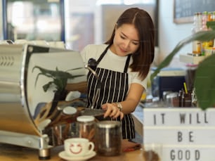 Portrait of female barista working with coffee machine in modern coffee shop