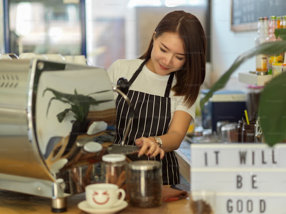 Portrait d’une femme barista travaillant avec une machine à café dans un café moderne