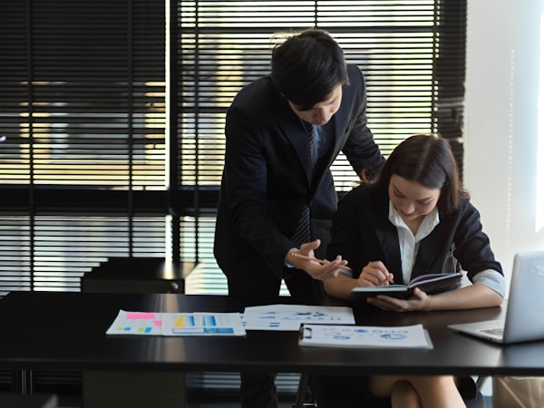 Business professionals reviewing project paperwork and a tablet together in an office — handling documents that may contain sensitive data