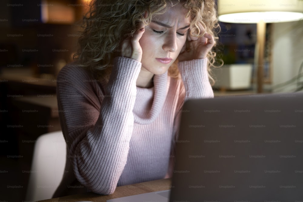 Femme fatiguée travaillant sur un ordinateur portable au bureau.