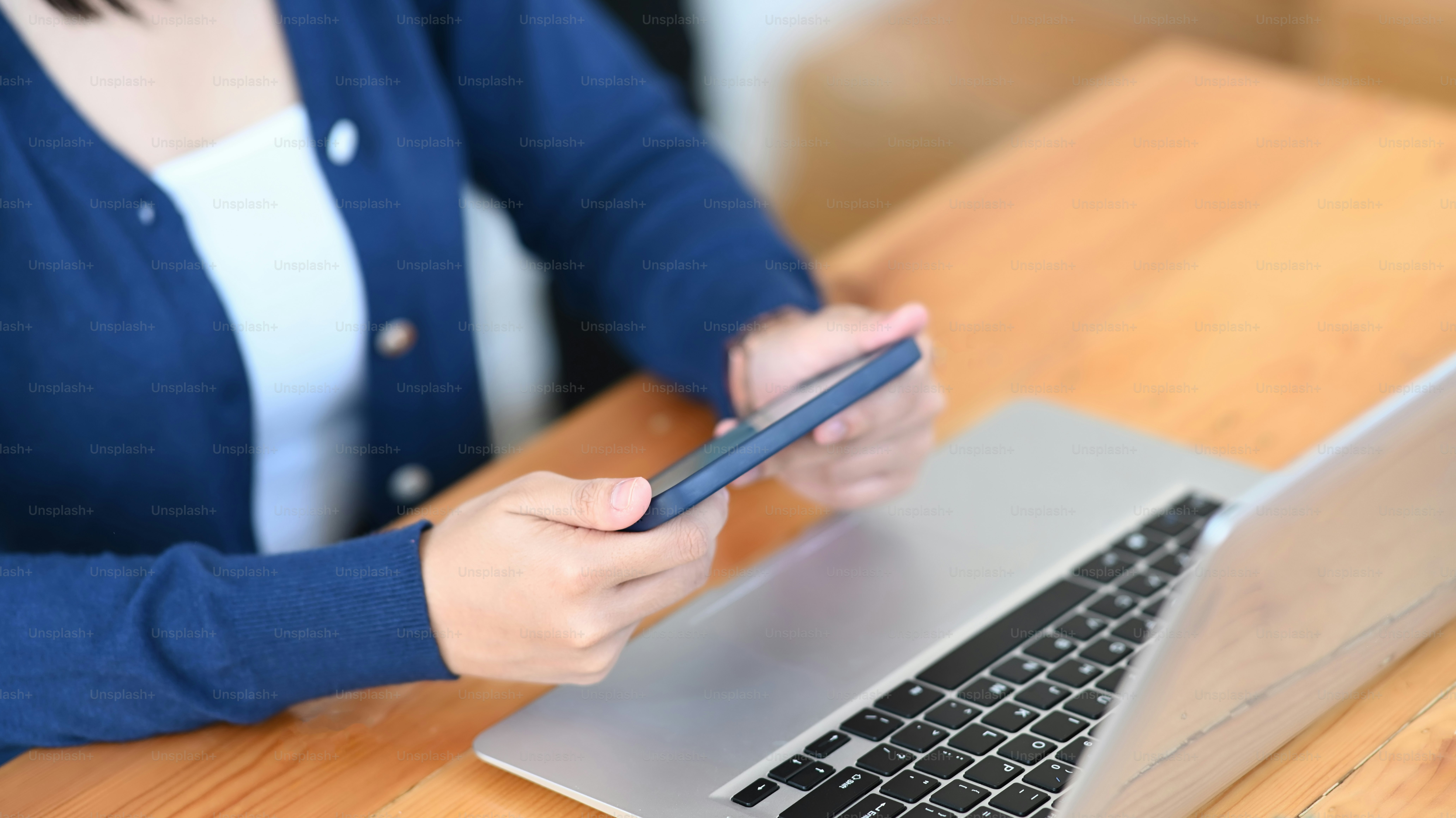 Vue rapprochée d’une jeune femme jouant à une application de jeu sur un téléphone intelligent tout en étant assise à son bureau.