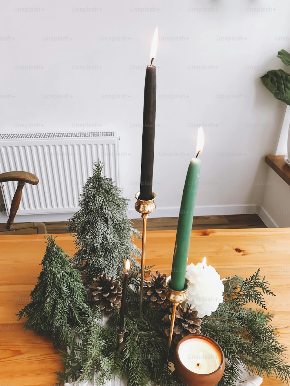 Christmas tree, candles, pine cones and fir branches on wooden table, christmas table setting and decor. Festive simple natural home decorations. Happy holidays and Merry Christmas!