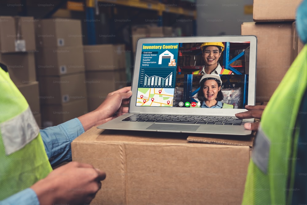 Warehouse staff talking on video call at computer screen in storage warehouse . Online software technology connects people working in logistic factory by virtual conference call on internet network .