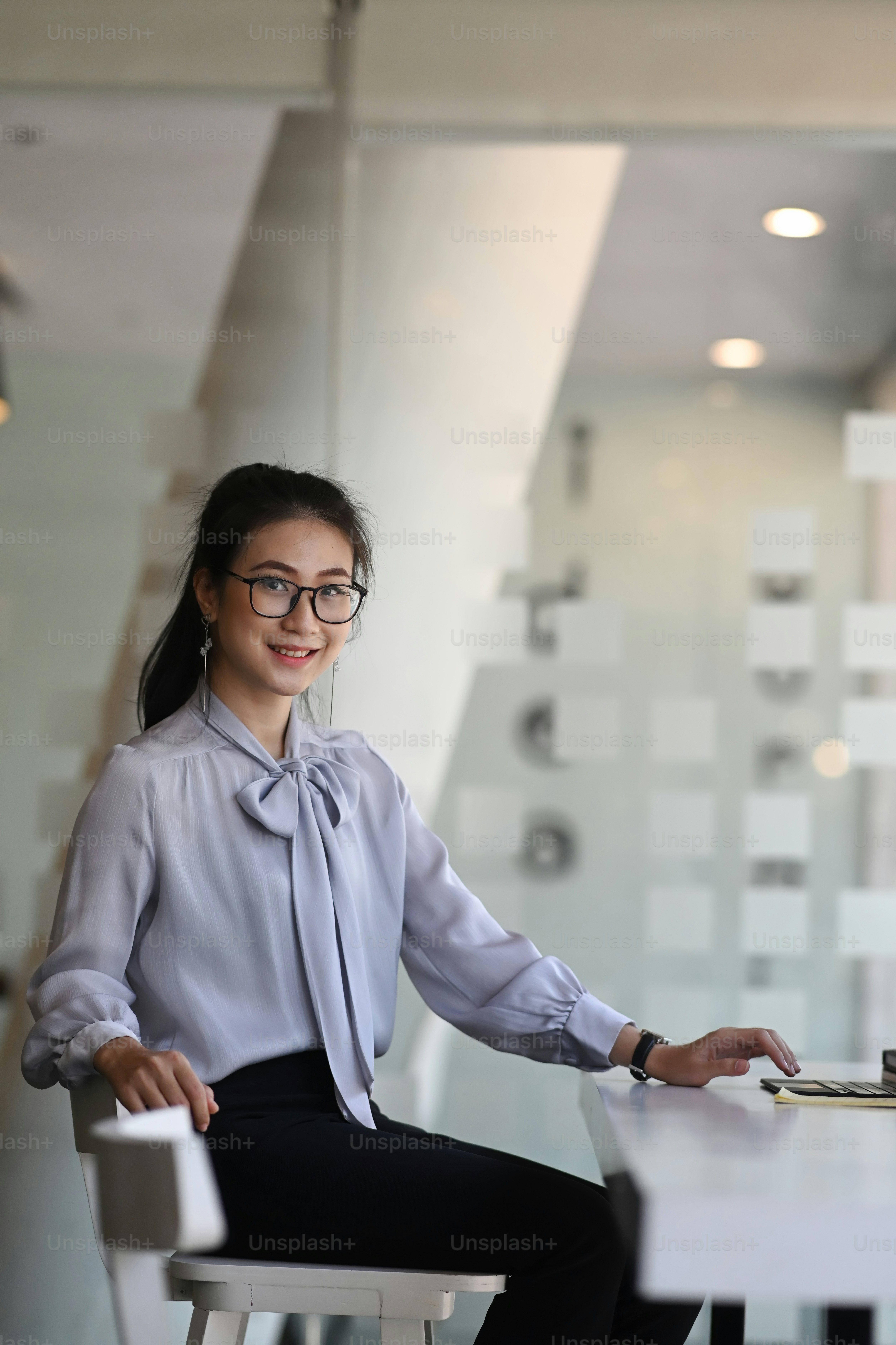 Portrait of an cheerful businesswoman sitting on office desk in casual and smiling to camera.