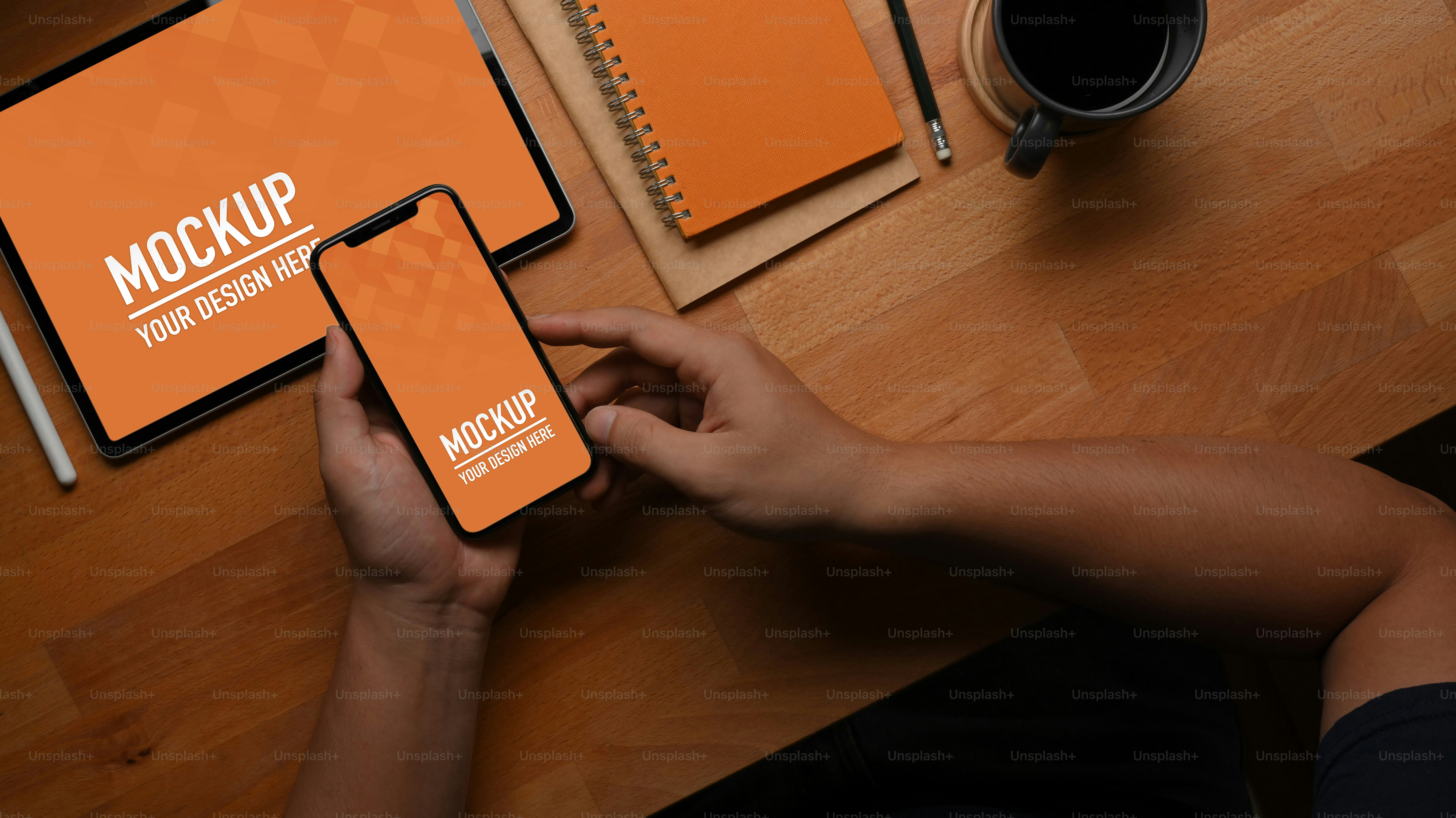 Vista dall'alto della mano maschile utilizzando lo smartphone sul tavolo da lavoro con tablet e cancelleria, percorso di ritaglio