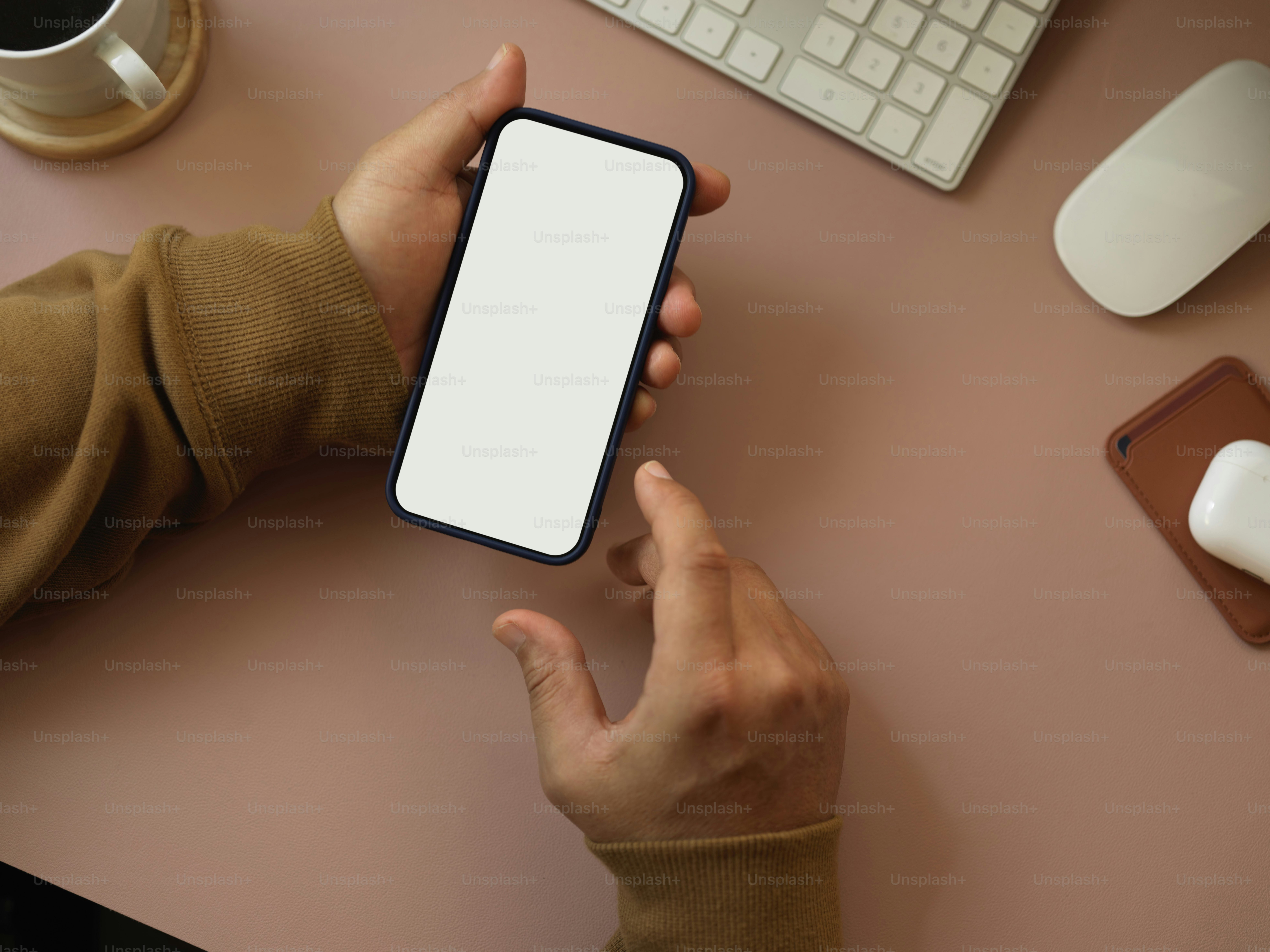 Vista dall'alto delle mani maschili che utilizzano lo smartphone sulla scrivania del computer, include il percorso di ritaglio