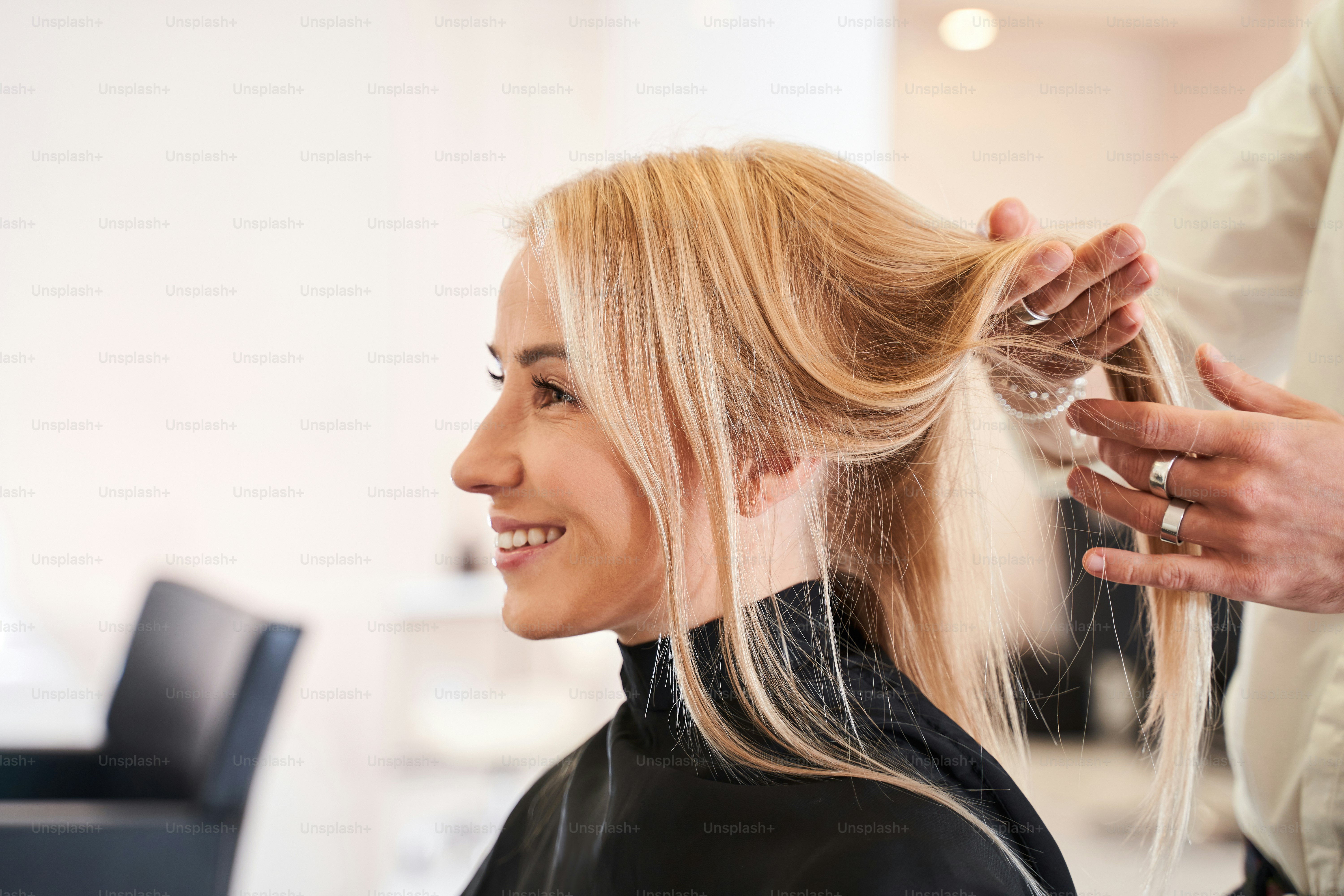 Tiene su propio estilista. Joven hermosa mujer discutiendo peinado con su peluquero mientras está sentada en la peluquería y se arregla el cabello