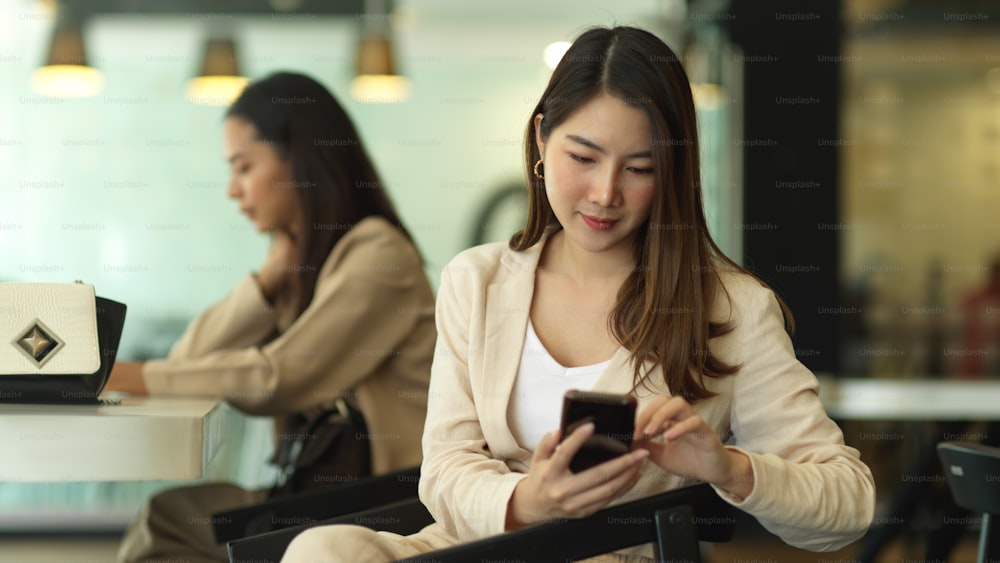 Portrait of businesswoman using smartphone while siting in meeting room