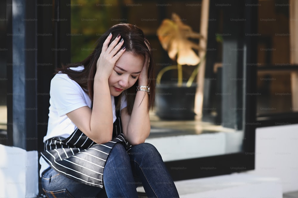 Jeune femme portant un tablier de serveuse se sentant désespérée et stressée.