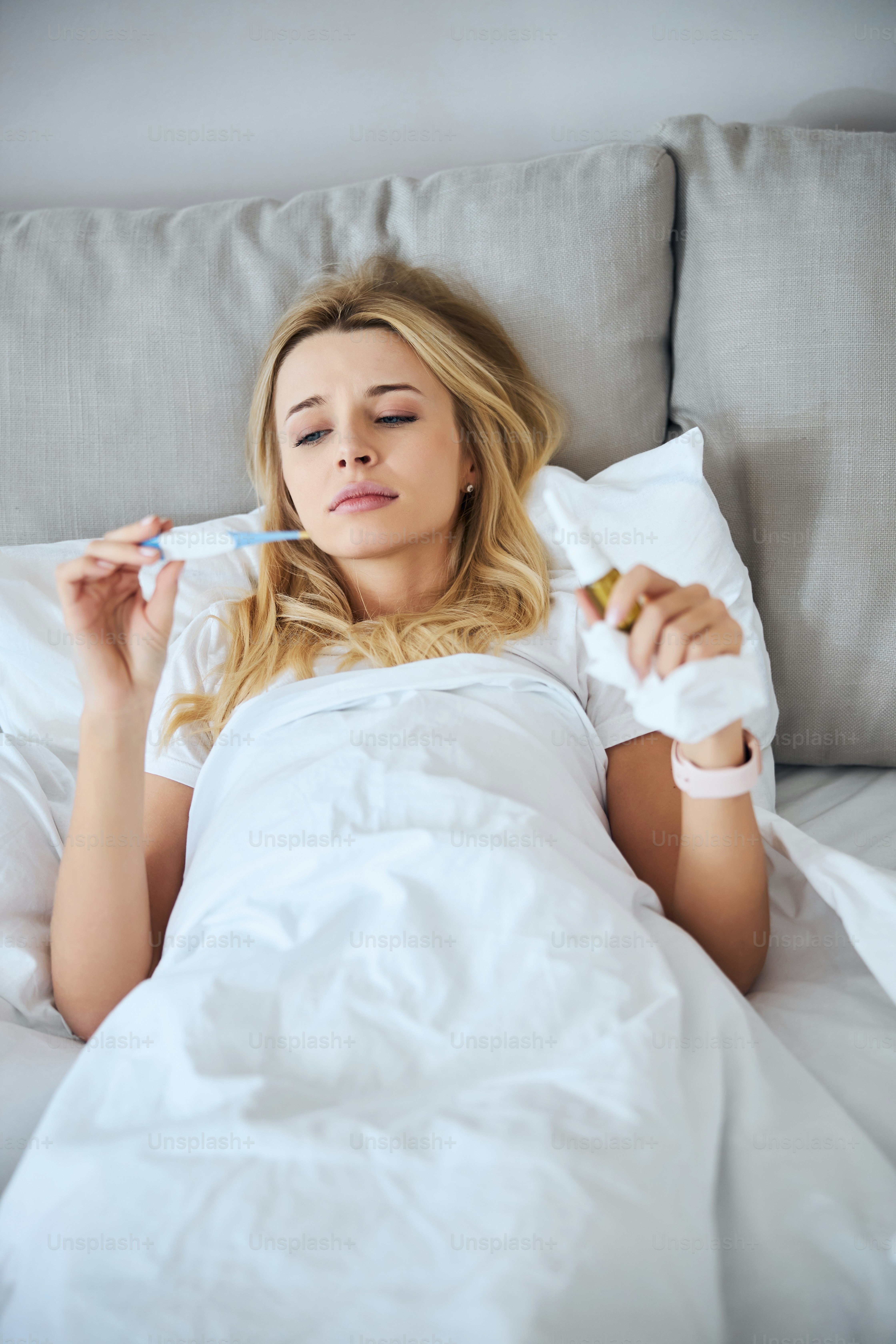 Kind female person keeping to her bed, treating herself with medicine