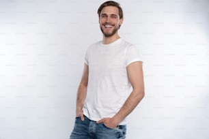 Homem bonito sorridente sexy na camiseta branca isolada no branco