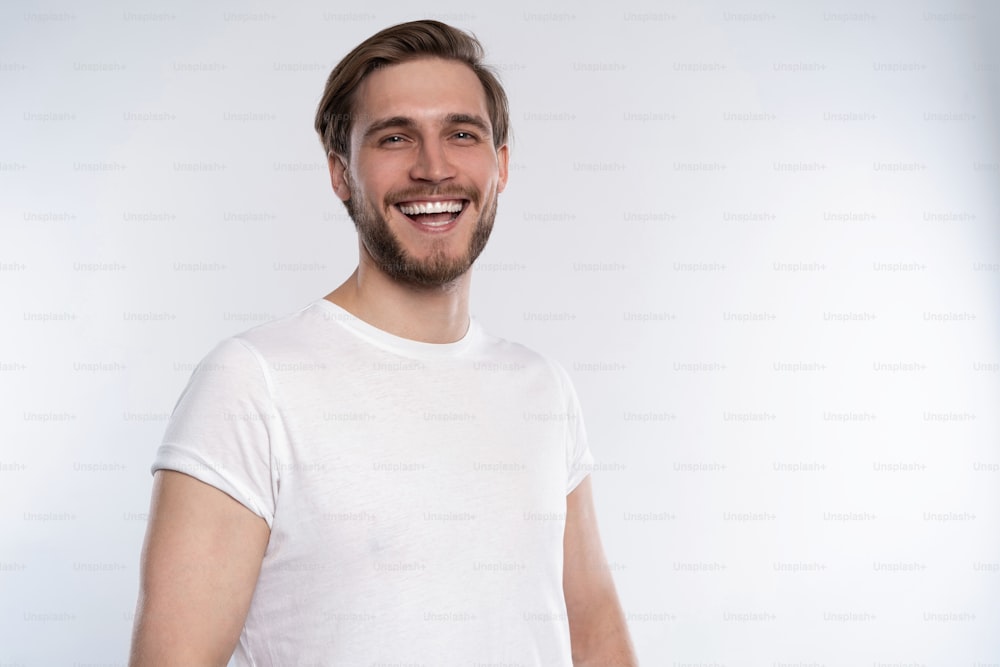 Homem bonito sorridente sexy na camiseta branca isolada no branco