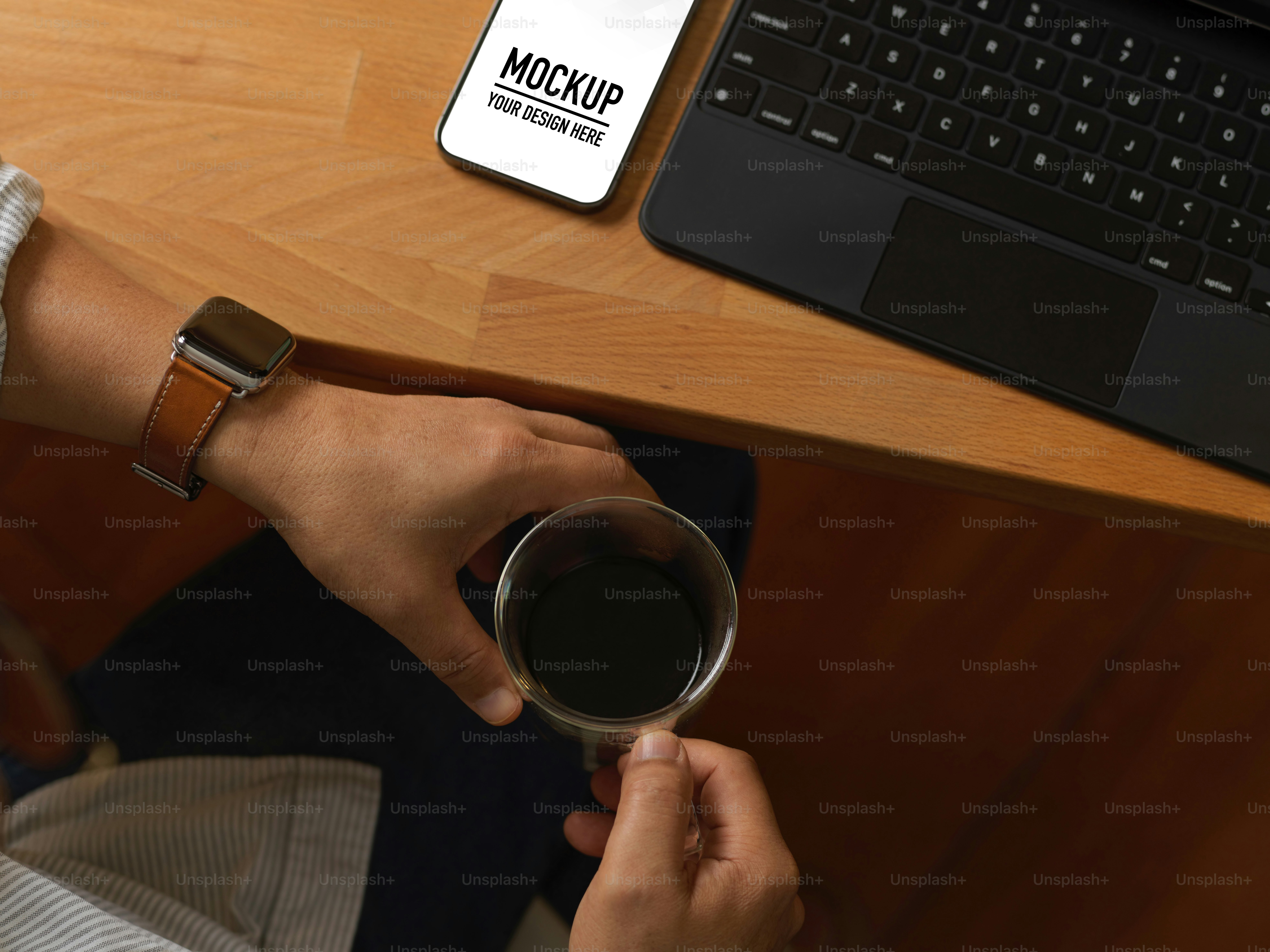 Vista dall'alto delle mani maschili che tengono la tazza di caffè mentre sono sedute al posto di lavoro con smartphone e laptop