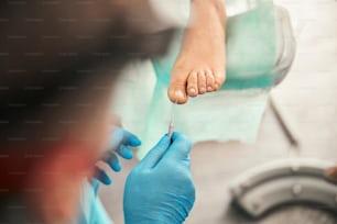 Close up of concentrated man wearing sterile gloves while doing foot care procedure