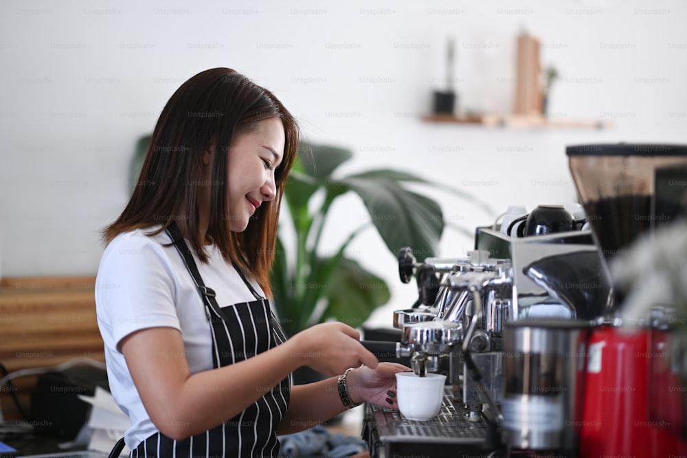 Professionelle weibliche Barista macht Tasse Kaffee mit Kaffeemaschine im modernen Café.