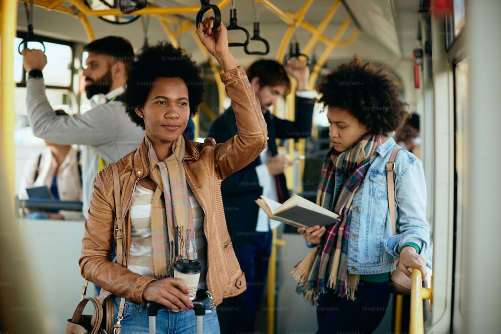 Mulher negra adulta carregando café para viagem enquanto se deslocava de ônibus.